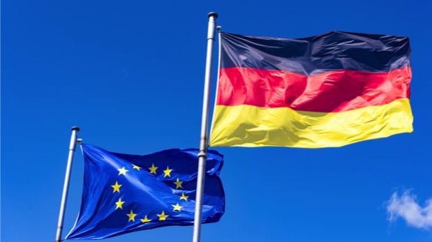 Flaggen der EU und Deutschland vor blauem Himmel.