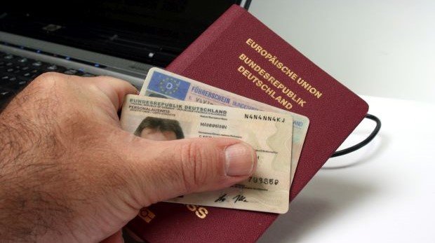 Mann hält Reisepass- Führerschein und Personalausweis in der Hand