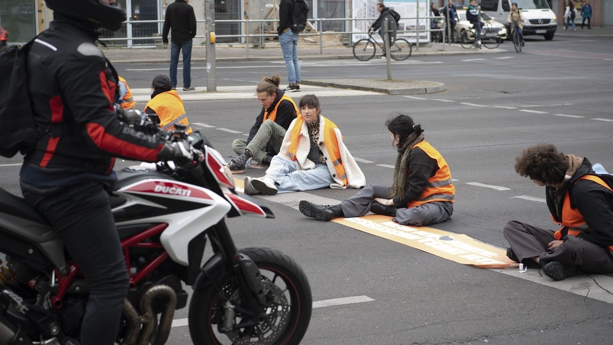 Bei einer Straßenblockade der Letzten Generation sitzen Aktivisten auf dem Mühlendamm auf der Straße. 16.05.2023