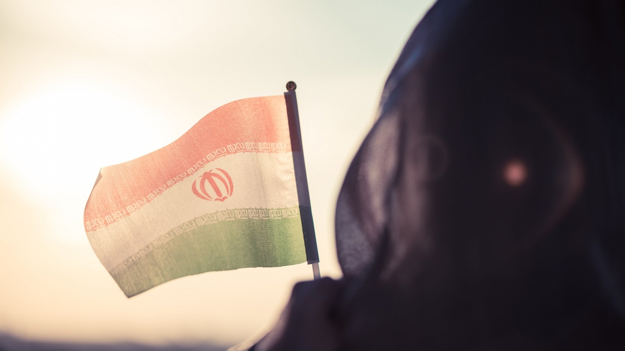 Frau mit Kopftuch und Iran-Flagge