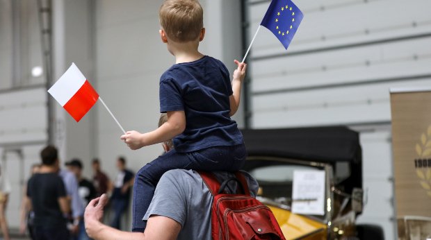 Ein kleiner Junge auf den Schultern seines Vaters mit einer Flagge Polens und einer Flagge der Europäischen Union