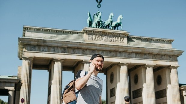 Ein Mann mit Handy vor dem Brandenburger Tor.