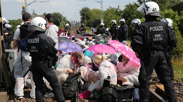 Klimaaktivisten und Teilnehmer des Klimacamps sitzen umringt von Polizei bei einem Protest auf Gleisen in Hamburg-Wilhelmsburg.