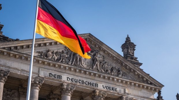 Gebäude des Bundestags in Berlin mit deutscher Nationalflagge.