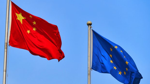 Flaggen von China und der EU nebeneinander vor blauem Himmel.