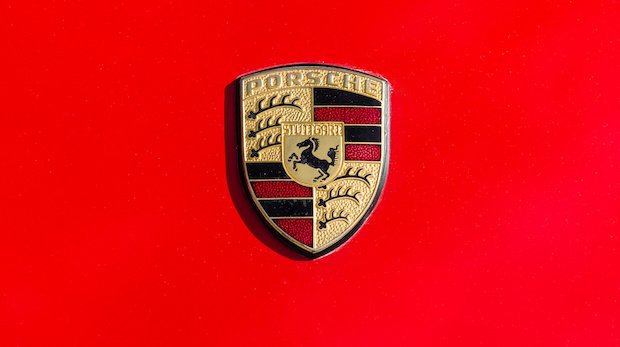 Logo des Unternehmens Porsche vor einem roten Hintergrund