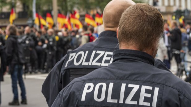 Polizisten auf einer Demonstration, wo die deutsche Nationalflagge mehrfach hochgehalten wird.