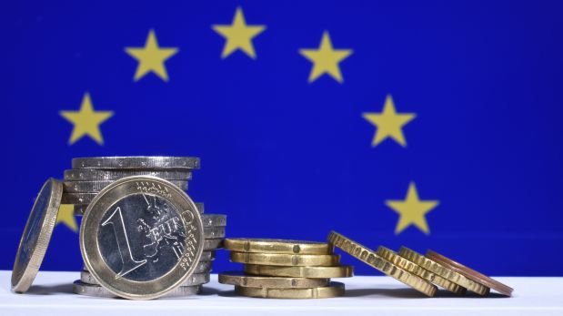 Flagge der EU mit Euromünzen auf einem Tisch im Vordergrund.