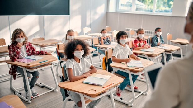 Schüler sitzen mit Masken in einem Klassenraum