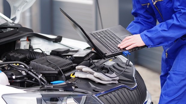 Mechaniker liest mit Laptop Daten aus einem Auto aus