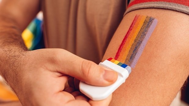 Mann malt sich eine Regenbogen-Flagge auf den Arm