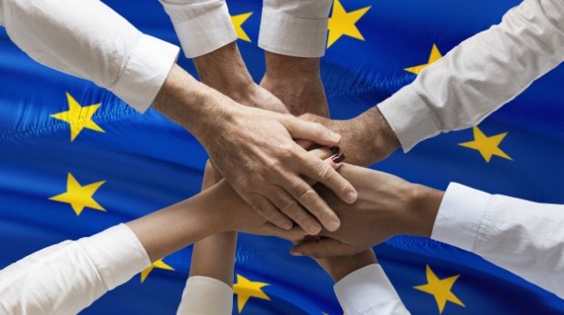 Zusammengelegte Hände über einer Europaflagge