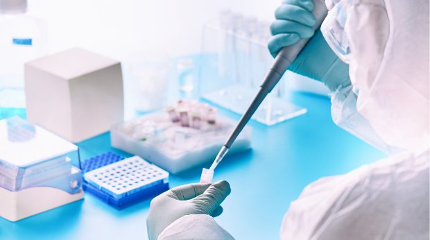 Eine Person im Schutzanzug führt in einem Labor einen PCR-Test durch