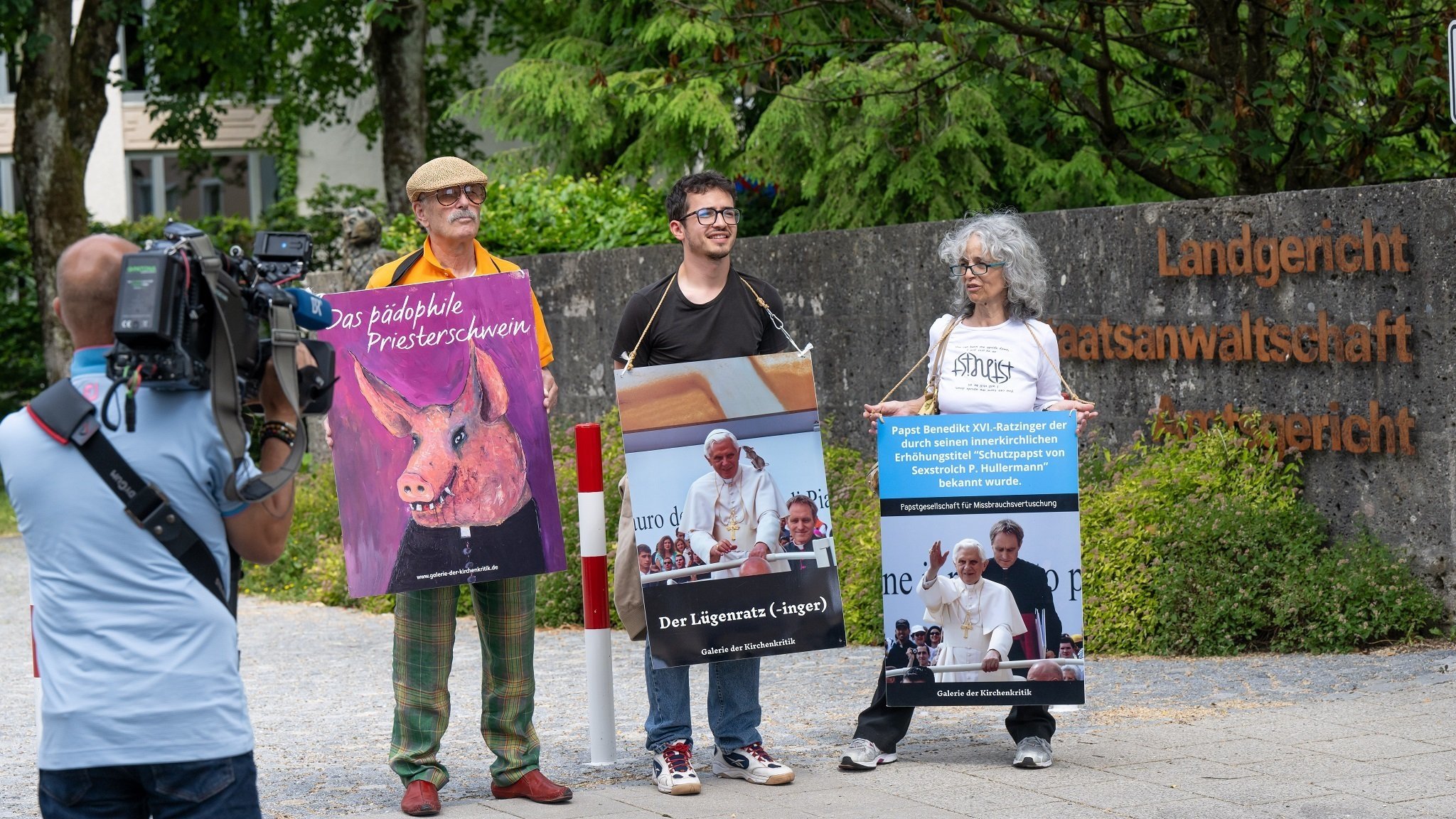 Drei Personen demonstrieren vor Beginn des Missbrauchsprozesses vor dem LG Traunstein.