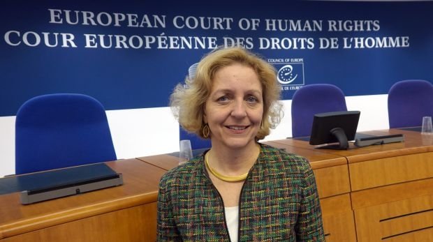 Angelika Nußberger, ehemalige Richterin am EGMR, steht vor der Richterbank im Saal der Großen Kammer.