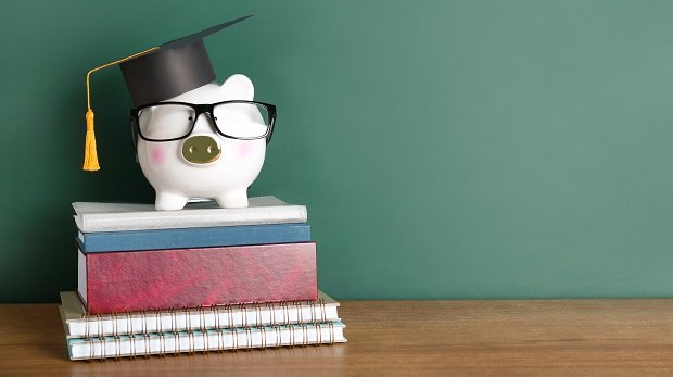 Sparschwein auf Büchern mit Brille und Absolventenhut