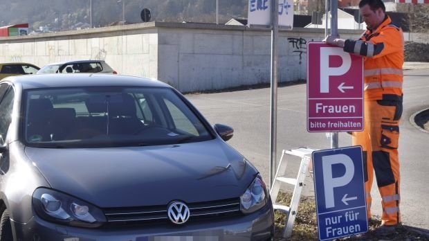 Bayern, Eichstätt: Ein Mitarbeiter der Stadt montiert an einem Parkplatz ein neues, pinkfarbenes Verkehrsschild.