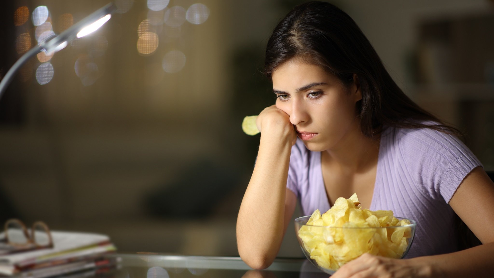 Traurige Frau mit einer Schüssel Chips (Symbolbild)