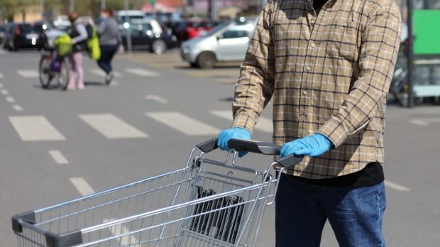 Mann mit Handschuhen und Einkaufswagen