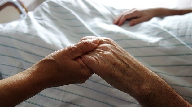 Frau hält die Hand eines Patienten im Krankenhaus