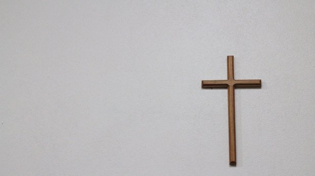 Ein schlichtes hölzernes Kreuz an einer weißen Wand