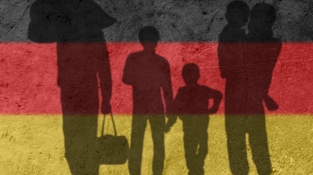 Silhouette einer Flüchtlingsfamilie vor Deutschland-Flagge