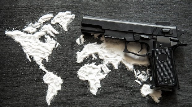 Pistole auf Weltkarte aus in Form gebrachtem Heroin