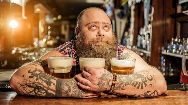 Selig blickender Mann umarmt drei Biergläser