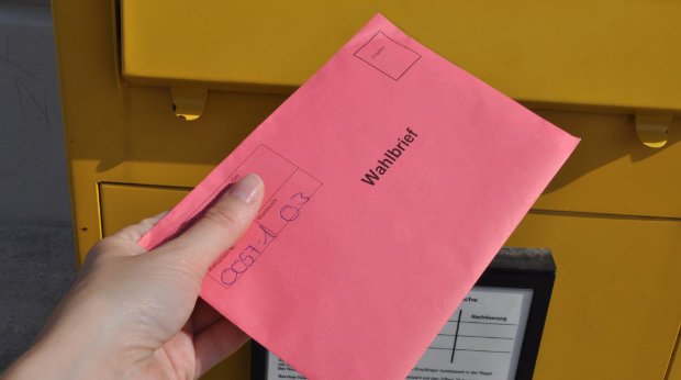 Ein Wahlbrief wird in einen Briefkasten eingeworfen
