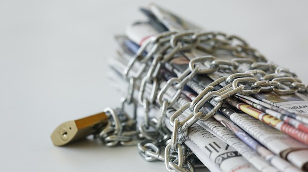 Zeitungen in Ketten als Symbol für Bedrohung der Pressefreiheit