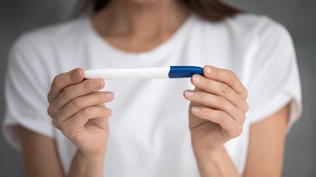 Eine Frau hält einen Schwangerschaftstest in der Hand.