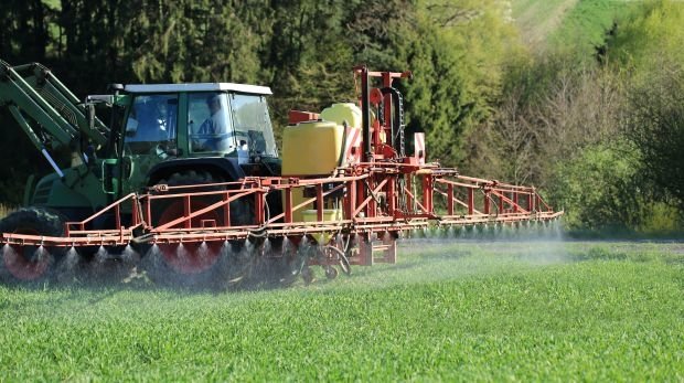 Traktor beim Spritzen von Pestiziden