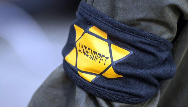 Bei einer Demonstration gegen die Einschränkungen durch die Pandemie-Maßnahmen der Bundesregierung am Brandenburger Tor trägt ein Teilnehmer eine Armbinde mit einem gelben Stern, der an einen Judenstern erinnern soll, mit der Aufschrift «Ungeimpft».