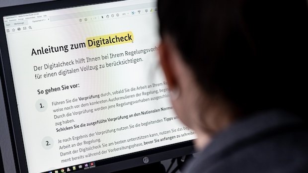 Ein Mitarbeiterin des Justizministeriums schaut auf einen Bildschirm mit dem Wort Digitalcheck.