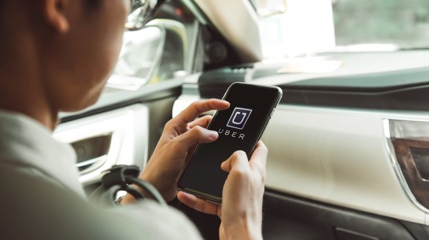 Autofahrer öffnet Uber-App (Symbol)