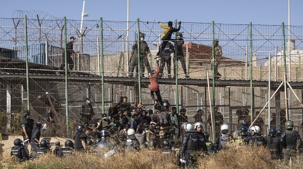 Menschen klettern über einen Zaun an der Grenze zwischen Spanien und Marokko (24.06.2022)