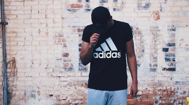 Ein Mann mit Adidas-T-Shirt vor einer Wand
