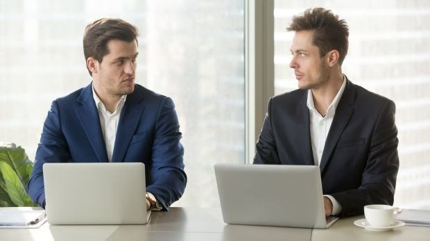 Zwei Männer sitzen im Büro nebeneinander
