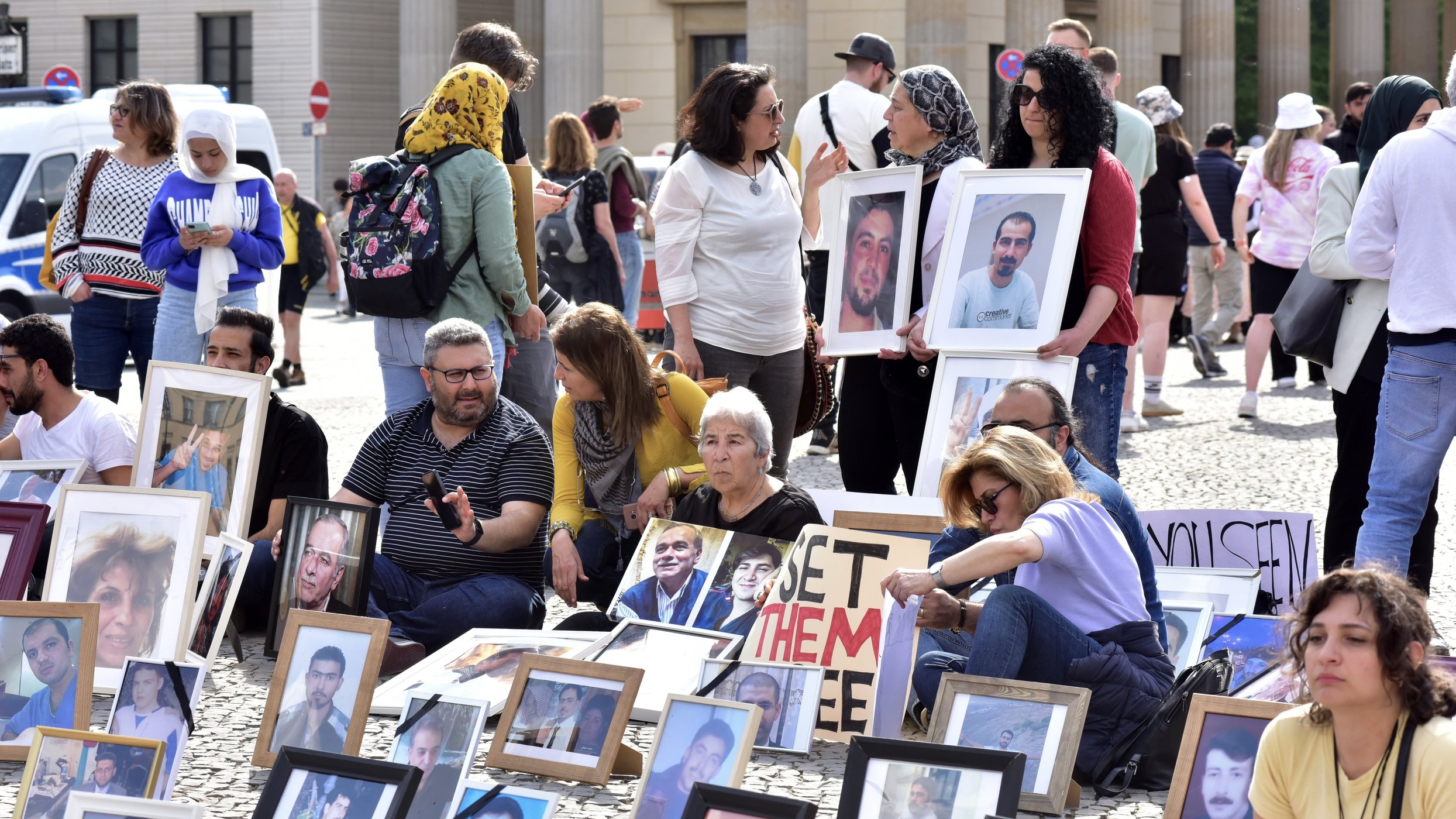 Syrische Aktivisten sitzen am 7. Mai 2022 in Berlin auf dem Pariser Platz hinter Portraits von vermissten Freunden und Verwandten