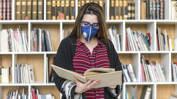 Studentin mit Maske in Bibliothek
