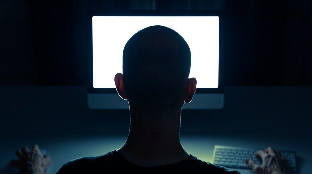 Ein Mann in dunklem Zimmer vorm PC (Symbolbild)
