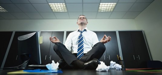 Mann meditiert auf Schreibtisch