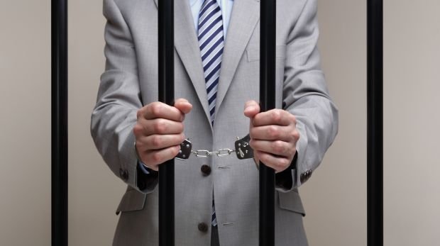 Mann im Anzug hinter Gittern (Symbolbild)