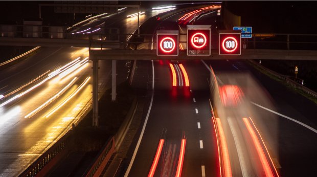 Eine Autobahn bei Nacht mit Tempo 100 Schildern