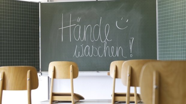 Schultafel in einem Klassenraum mit der Botschaft, sich bitte die Hände zu waschen