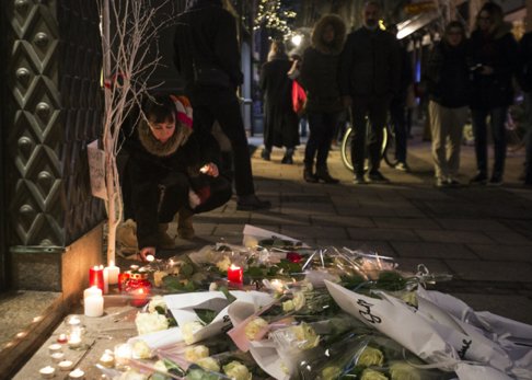 Eine trauernde Person zündet eine Gedenkkerze auf dem Weihnachtsmarkt in Straßburg, Frankreich, an.