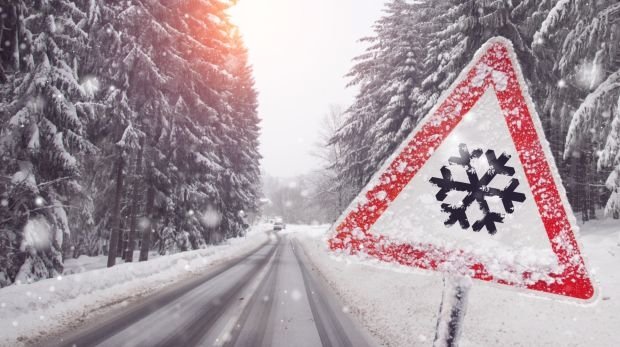 Schneebedeckte Straße und Warnschild
