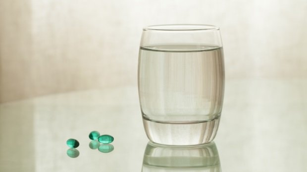 Abführmittel neben Wasserglas (Symbol)