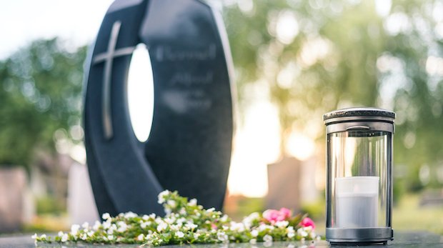 Ein Grabmal mit Blumen und einer Kerze (Symbolbild)