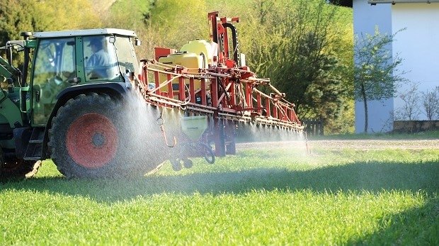 Traktor bespritzt Feld mit Pflanzenschutzmitteln